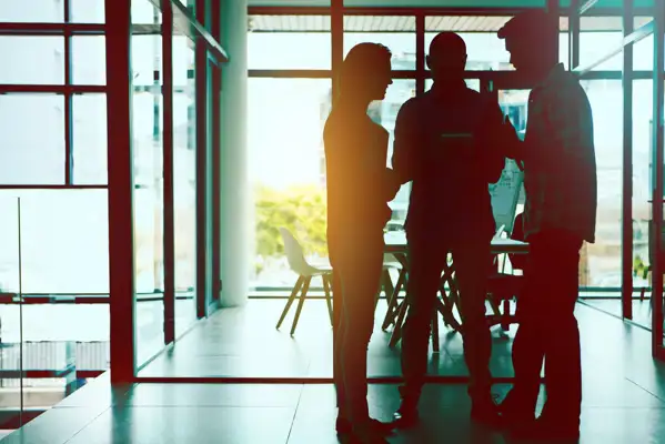 Three people huddled talking together in a office