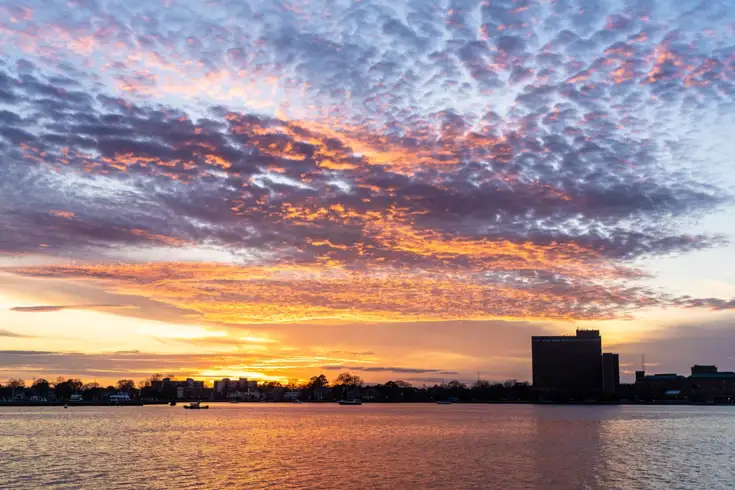 View of the yellow sky with city landscape and boats on the water