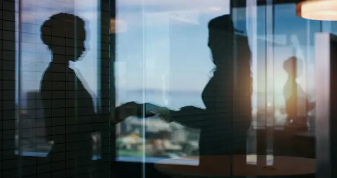 Blurry image of two people exchanging a document