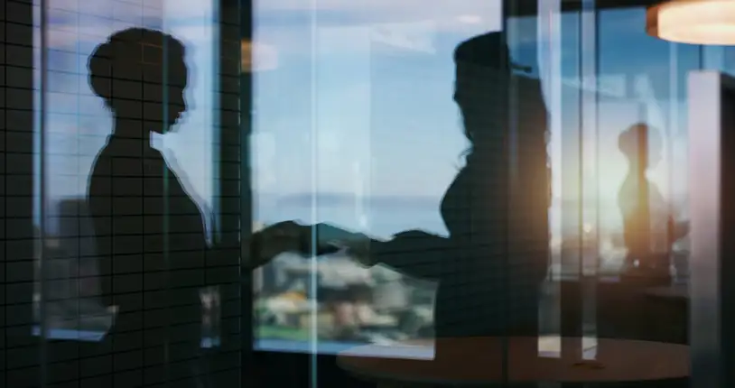 Blurry image of two people exchanging a document